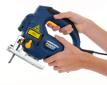 Hands demonstrating an electric jigsaw